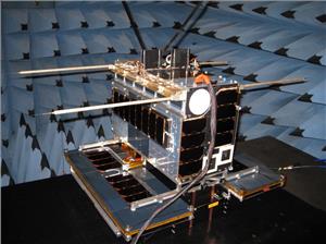 NORsat-1 in EMC test at SFL. Two AIS antennas may be seen at the top, and four Langmuir probes off to the sides. The solar wings of the satellite are at the bottom. (Photo: Space Flight Laboratory)