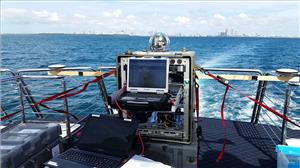 The TREC test assembly shown on the charter vessel as it enters the Port of Miami. Researchers established communications links with a similar terminal located on the roof of one of the buildings in the distance. (Photo: U.S. Naval Research Laboratory)